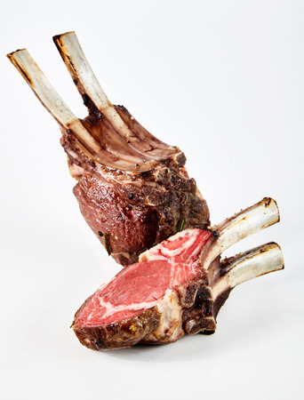 Barbecued or roasted lamb chops, trimmed for excess fat and cut through to show the tender succulent meat over whiteの写真素材