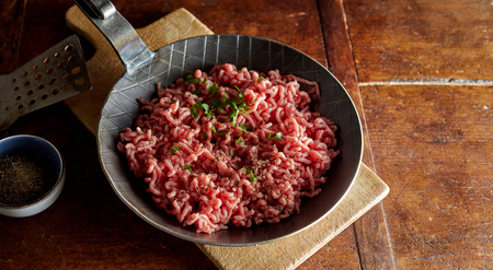 Raw minced meat with chives prepared on pan in kitchenの写真素材