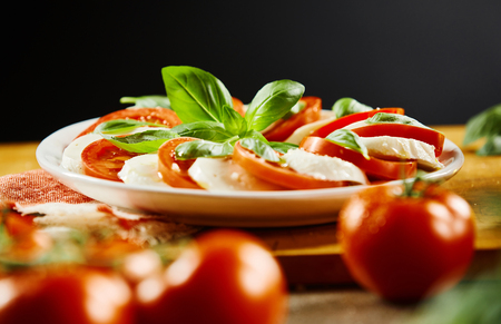 Plate of Italian Caprese salad with alternating sliced tomato and mozzarella cheese garnished with basil in a low angle viewの写真素材