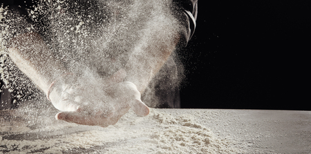 Cloud of flour caused by unidentified man cleaning off hands hands over table already covered in white powder