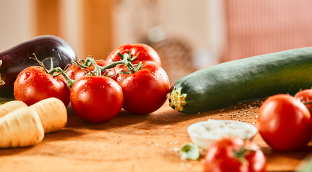 Assorted fresh vegetables on a wooden counter with zucchini, tomatoes, turnips, and brinjal or egg plant in banner formatの写真素材