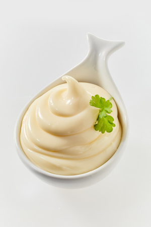 Twirled freshly made mayonnaise in a ceramic spoon to be served as an accompaniment to a formal mealの写真素材
