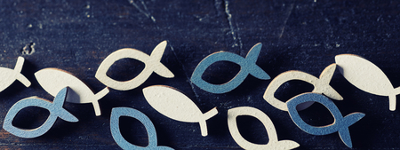 Blue and white cut out Christian religion fish symbols in a row on dark blue backgroundの写真素材