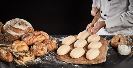 Raw dough for loaves of bread on a wooden paddle ready to be placed in the oven for baking held in...