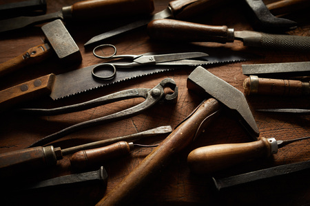 Collection of vintage woodworking hand tools with wood handles arranged on a rustic wooden workbench...
