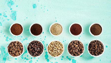 Coffee still life with roasted and raw beans and grounds neatly displayed in separate bowls in two...