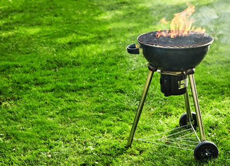 Burning fire with flames in a portable BBQ outdoors on a green spring lawn with copy spaceの写真素材