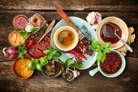 Assorted spicy marinades, sauces and rubs with fresh ingredients, herbs and spices for a summer barbecue in a food still life on rustic wood viewed from aboveの写真素材