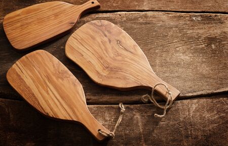 Three clean empty wooden chopping boards on an old rustic or vintage wood background viewed from...