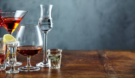 Assorted alcoholic beverages on rustic bar counter with copy space over textured slate behind in a panorama bannerの写真素材