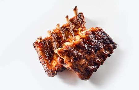 Delicious spicy marinated grilled ribs in two portions fresh from a barbecue arranged on a white background for advertisingの写真素材
