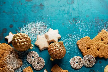 Christmas food border with traditional baked cookies, ornaments and sprinkled sugar over a cool blue winter background with copy space for a greeting card or invitationの写真素材