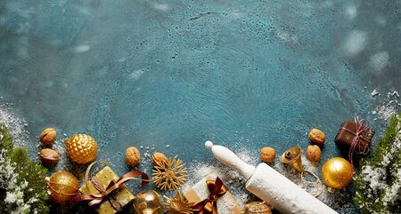 Festive Christmas border with snow on cool blue with pine branches, decorations, nuts, gifts and a rolling pin with copy space for a holiday messageの写真素材