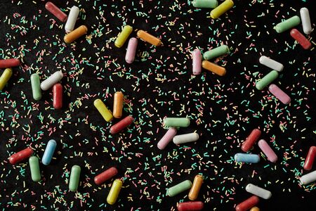 Full frame candy  texture on black with scattered baking sprinkles and sugar-coated liquorice in a random patternの写真素材
