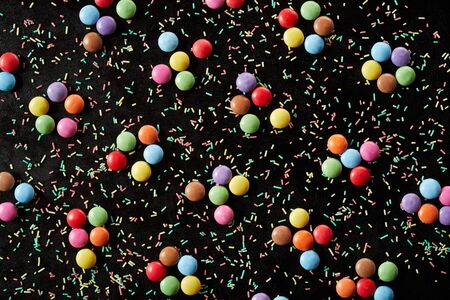 Scattered cooking sprinkles with colorful round sugar-coated chocolate candy arranged in groups of...