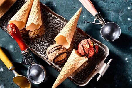 Two assorted flavors of Ice-cream, wafer cones or cornets and scoops in a top down still life on a trayの写真素材