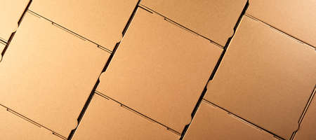 Panorama banner with unlabelled new recyclable brown cardboard pizza boxes packed symmetrically in a...