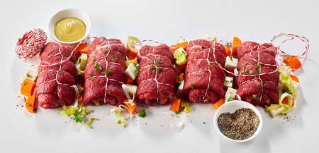 Ingredients and trimmings for beef roulades viewed as a flat lay still life on white in a panorama bannerの写真素材
