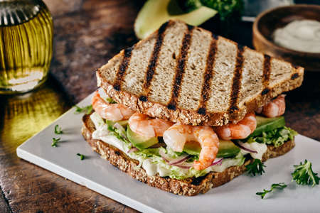 Spicy Italian salami sausage and cheese on a sandwich with salad trimmings and sliced zucchini or cucumber in a side view isolated on white for advertisingの写真素材