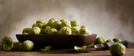 High angle of fresh raw cut chicken liver with cartilages in wooden pet bowl placed on table with uncooked ripe veggiesの写真素材