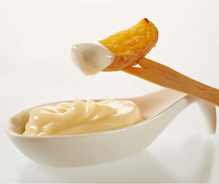 High angle of delicious deep fried potato slices with tomato salsa and mayonnaise near organic fork on white backgroundの写真素材