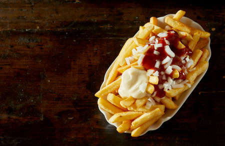 Top view of delicious golden fried potatoes garnished with ketchup and mayo and served with fresh...