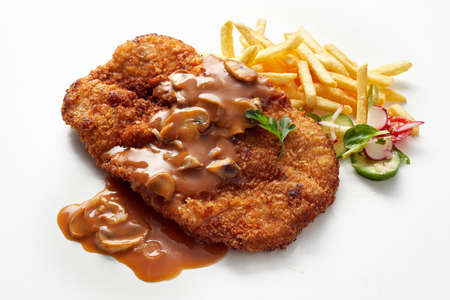 Closeup of traditional German dish veal schnitzel with aromatic chasseur sauce with champignons served with French fries and saladの写真素材