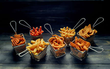 High angle of different types of French fries placed near roast chicken served with lettuce leaves and sauces on tableの写真素材