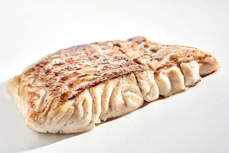 Closeup yummy freshly fried pollack fish steak with crispy crust placed on white backgroundの写真素材
