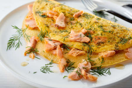 Closeup of delicious omelette with salmon and dill served on plate on white table