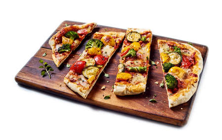 From above of tasty vegetarian pizza with assorted vegetables placed on wooden chopping board on...