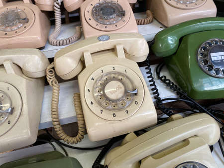 Composition of many old rotary telephones arranged on wooden shelves in light roomの写真素材
