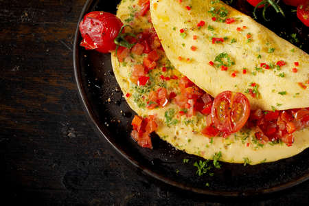 Top view of tasty vegan omelette with herbs and tomatoes on plate placed on tableの写真素材