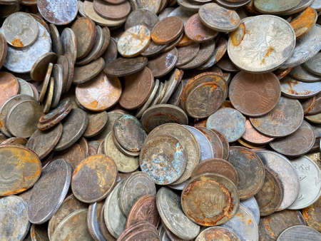Top view composition of many weathered rusted coins of different nominal values heaped together in bright lightの写真素材