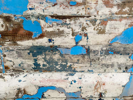 Textured background of facade of building with wooden surface with white and blue peeling paint