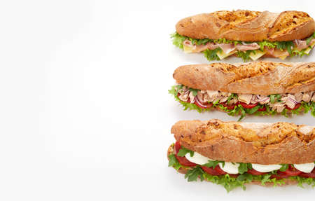 Top view of tasty assorted submarine sandwiches with meat and vegetables placed on white background in studioの写真素材