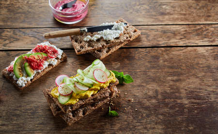From above of various delicious crispbread toasts with vegetables served on wooden table for vegetarian snackの写真素材