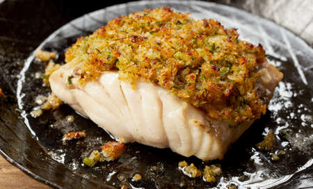 Delicious yummy baked cod fish fillet with coating breadcrumbs served on ceramic plate