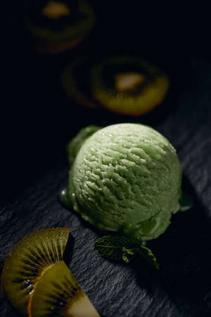 From above of tasty gelato ball with creamy texture between fresh ripe kiwi slices on blurred backgroundの写真素材