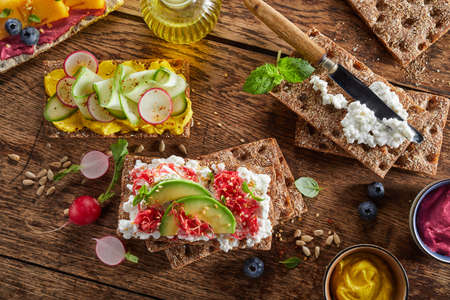Top view of arrangement of various delicious crispbread toasts with vegetables served on wooden table for snackの写真素材