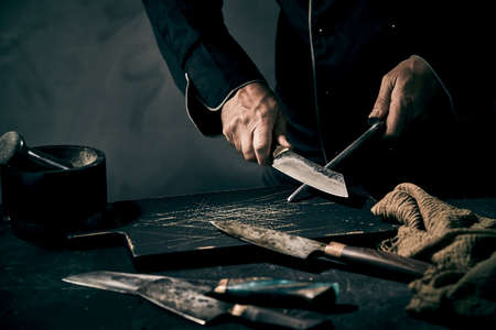 Chef preparing a fresh seafood soup or broth for an appetizer holding a whole fresh fish above a stainless steel pot surrounded by assorted fresh vegetable ingredientsの写真素材