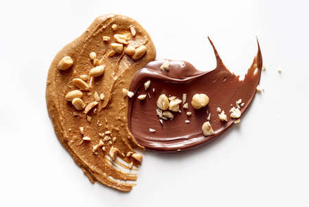 Top view of tasty peanut butter and chocolate paste sprinkled with crushed nuts placed on white tableの写真素材