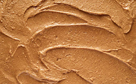 Closeup top view of full frame textured background of yummy soft peanut butter