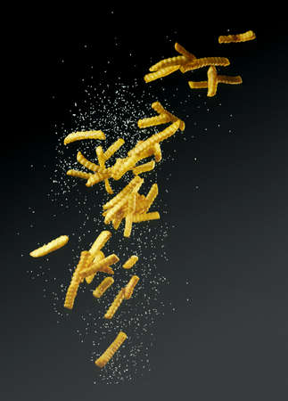 Flying fries or french fries with salt on a dark background for takeaway advertising and burger...