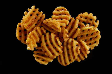 Top view portion of appetizing spicy potato grids with crispy crust placed on black surfaceの写真素材