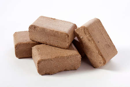 Stack of solid peat fuel biomass briquettes arranged against white background in studio