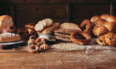 Slices of freshly baked Turkish bread with assorted sweet pastries served on messy wooden table with...