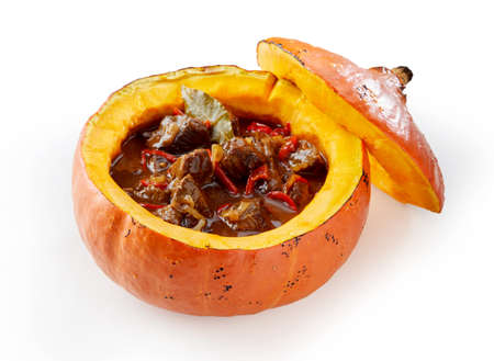 High angle of yummy meat goulash with vegetables and bay leaf served in small pumpkin on white backgroundの写真素材