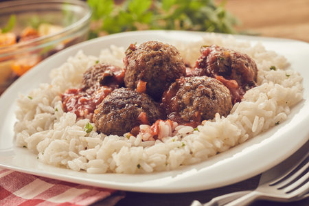 Closeup tasty boiled rice and meatballs with tomato sauce served for lunch on plate at homeの写真素材