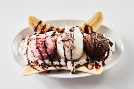Top view of plate with colorful ice cream scoops and banana slices served on white background